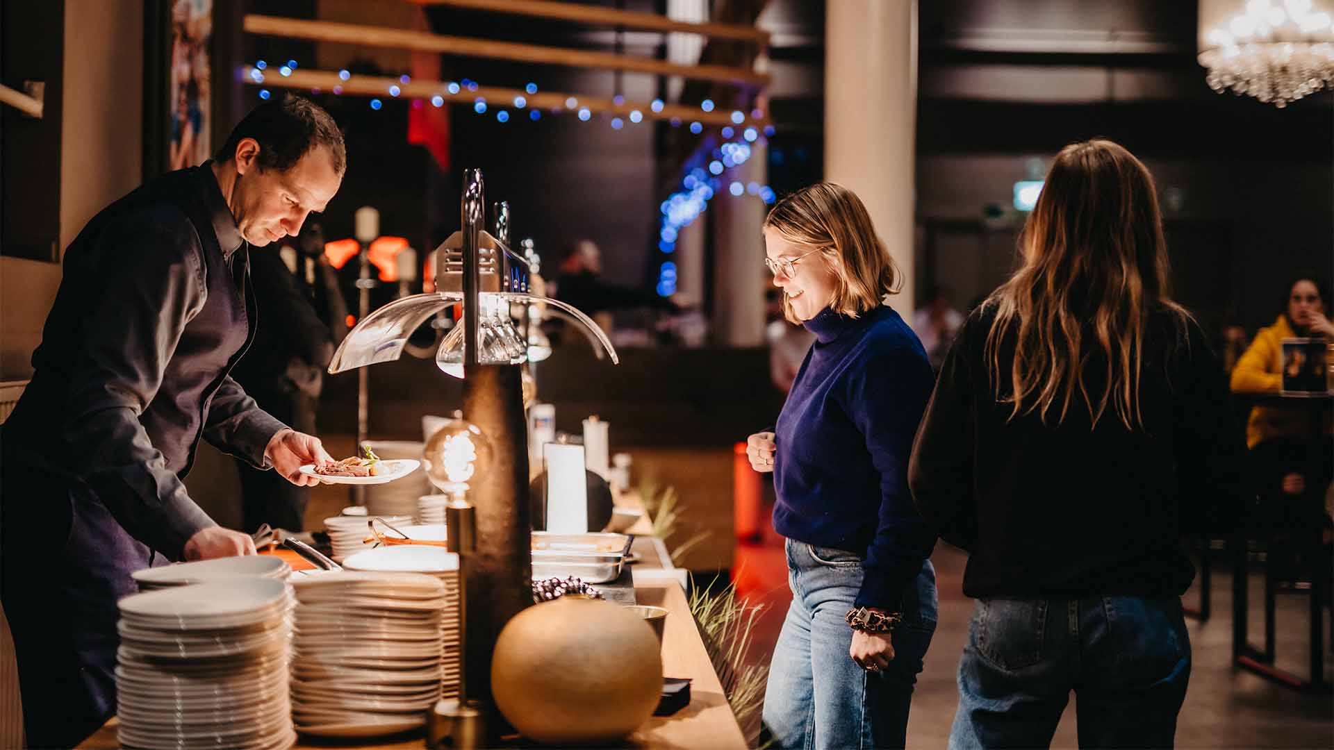 Een vrouw wacht aan de buffettoog terwijl een ober eten voor haar opschept.
