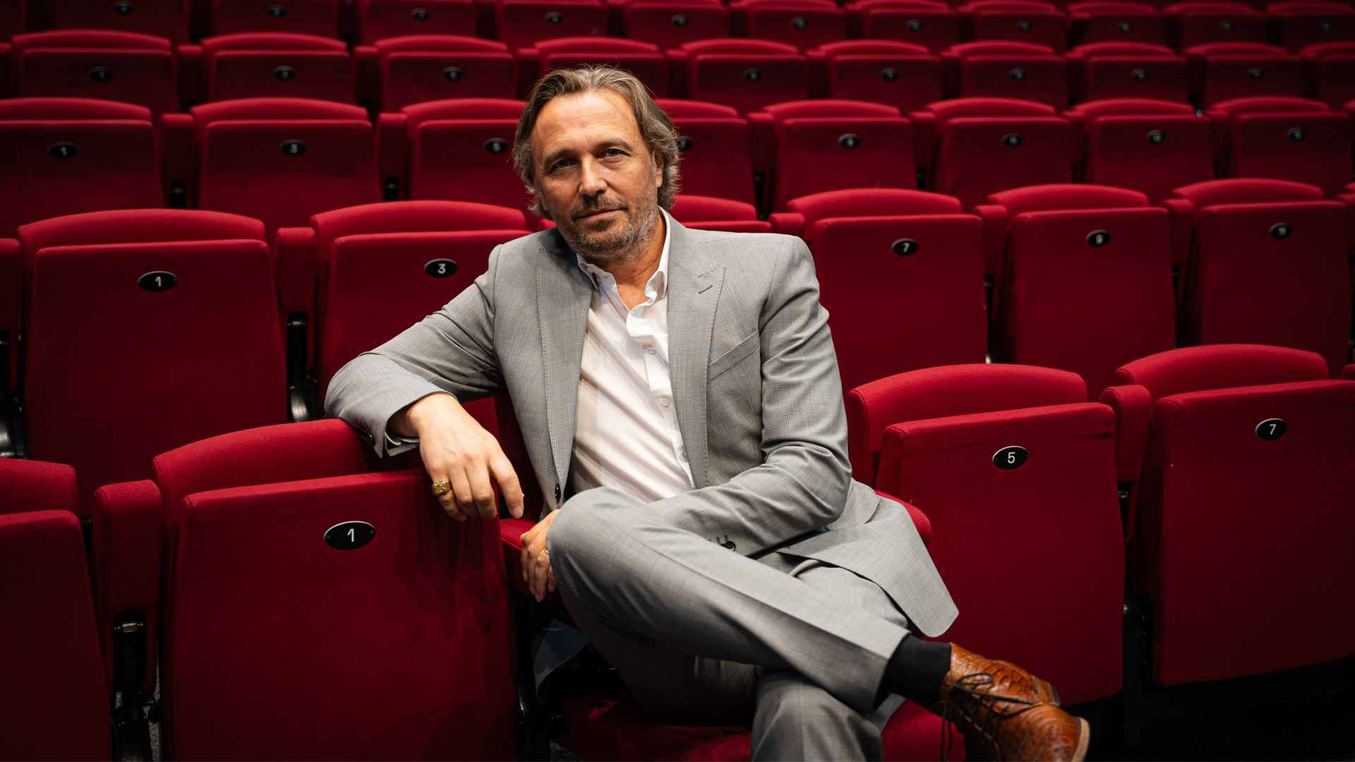 Dieter Troubleyn zit tussen de rode theaterstoelen van Stadsschouwburg Antwerpen naar aanleiding van zijn rol als Juan Perón in de musical ‘Evita’.