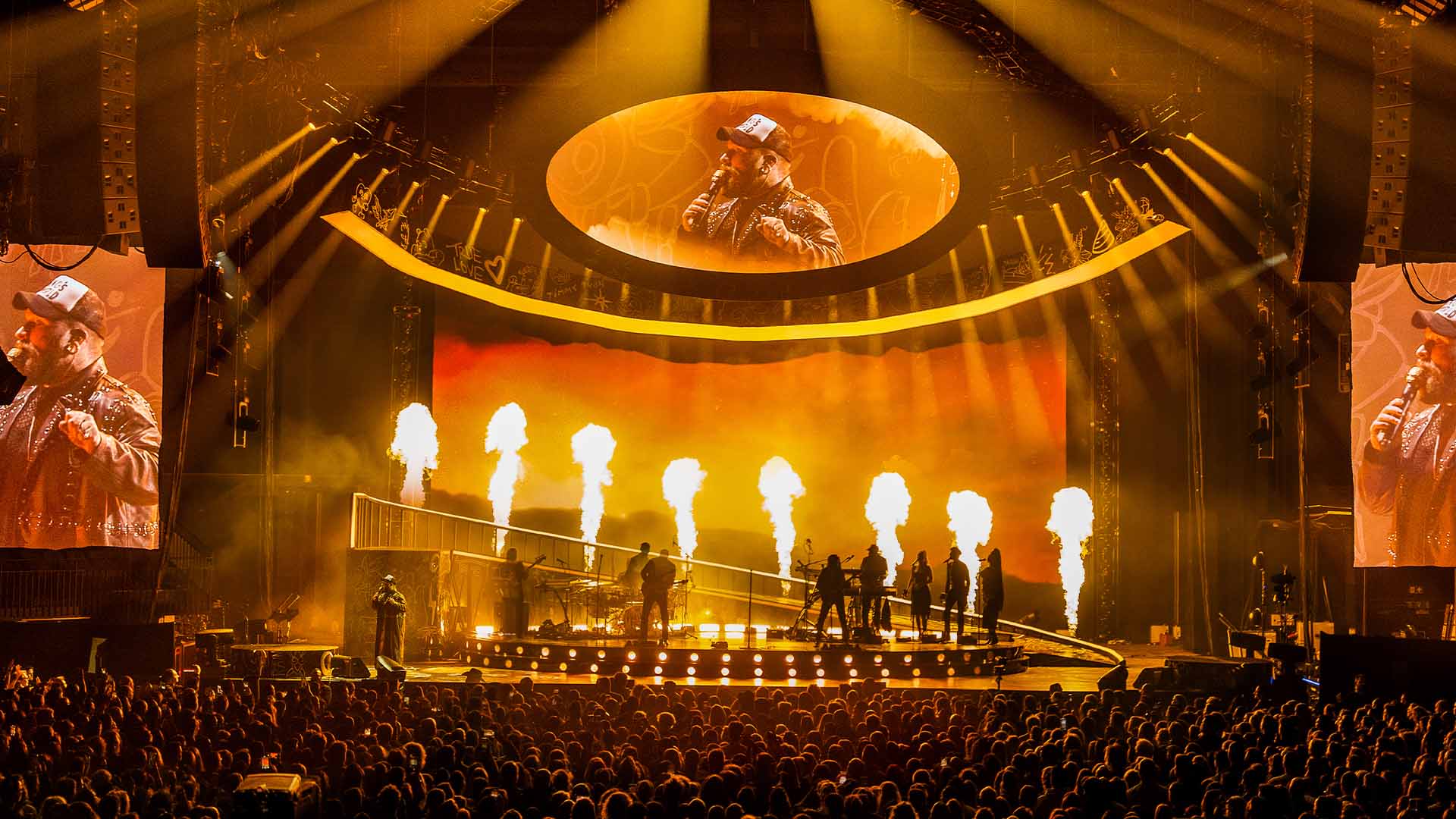 Teddy Swims and his band are on stage at the Lotto Arena. Flames can be seen behind the band members.