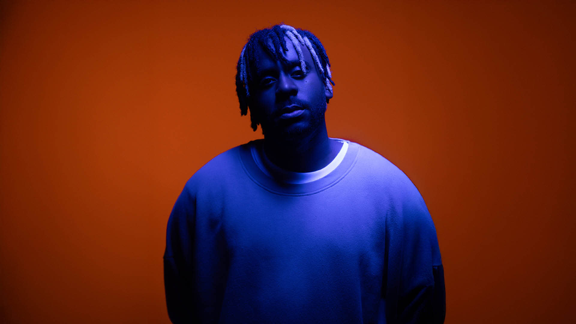 Portrait de Myles Smith en lumière bleue sur fond orange