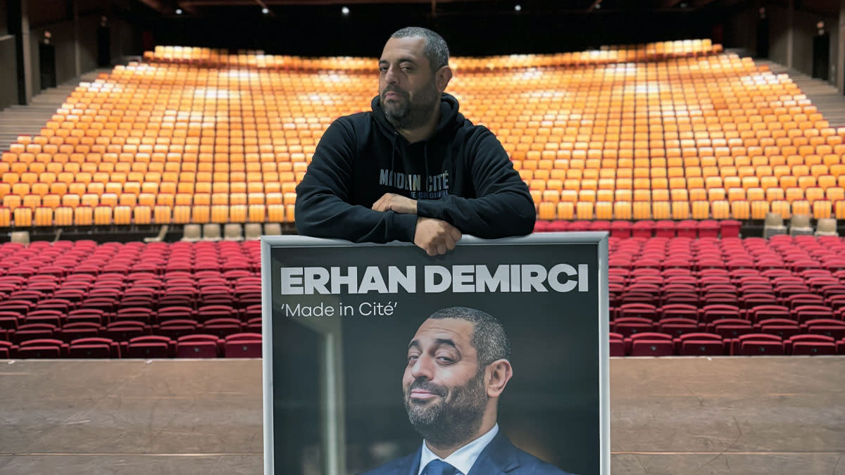 Comedian Erhan Demirci pronkt met een poster van zijn nieuwste show in de theaterzaal van Trixxo Theater.