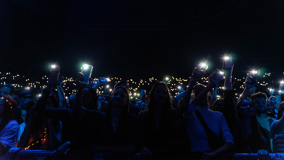 Un public enthousiaste lors d’un concert, levant leurs smartphones allumés dans l’obscurité.