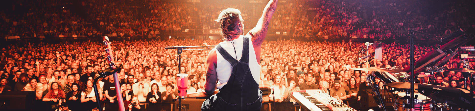 Sold-out crowd at Forest National during a live concert, with thousands of cheering fans and an artist performing on a lit stage.