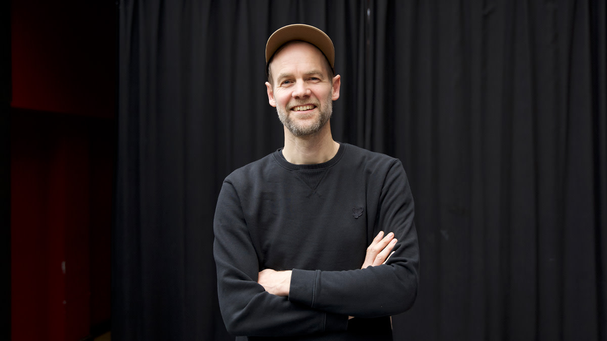 Wannes Cappelle van Het Zesde Metaal poseert in een zwarte trui voor een donker doek in Capitole Gent.