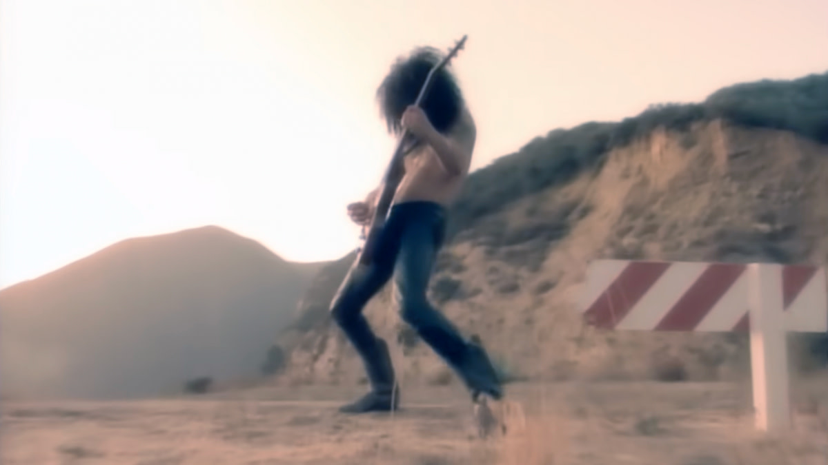 Gitarist Slash van Guns 'N Roses in zijn typische houding middenin een gitaarsolo in de video bij het nummer 'Don't Cry'.