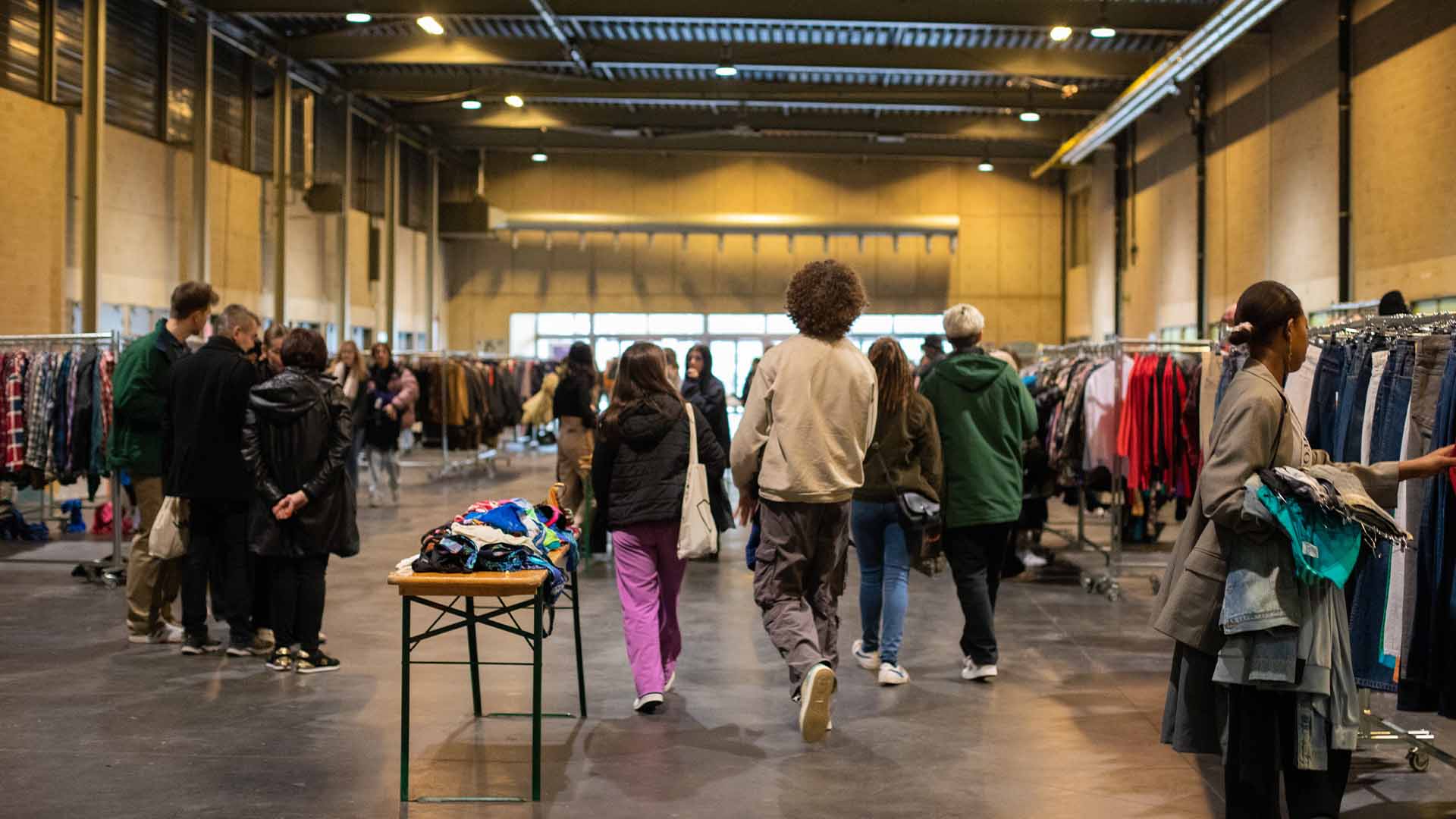 Several people are browsing through racks of vintage clothing.