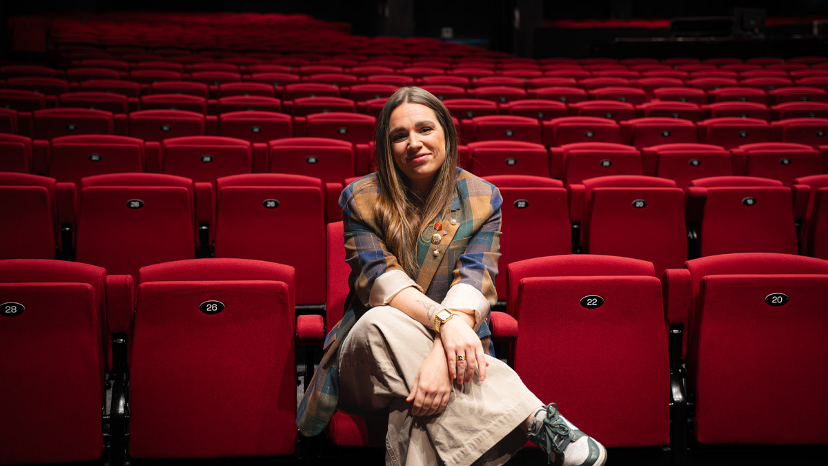 Lisa Van Rossem, aka LEEZ, zit relax in de rode theaterstoeltjes van Stadsschouwburg Antwerpen.