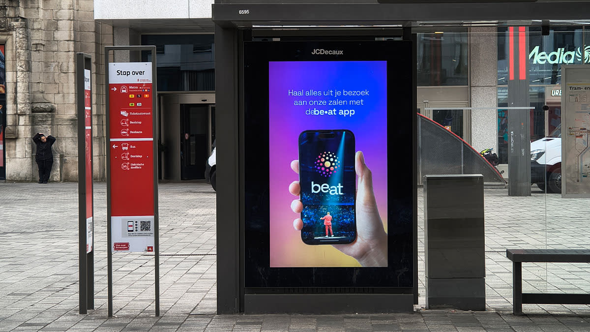 Bushalte in Antwerpen waarop een groot scherm promotie wordt gemaakt voor de be•at App.
