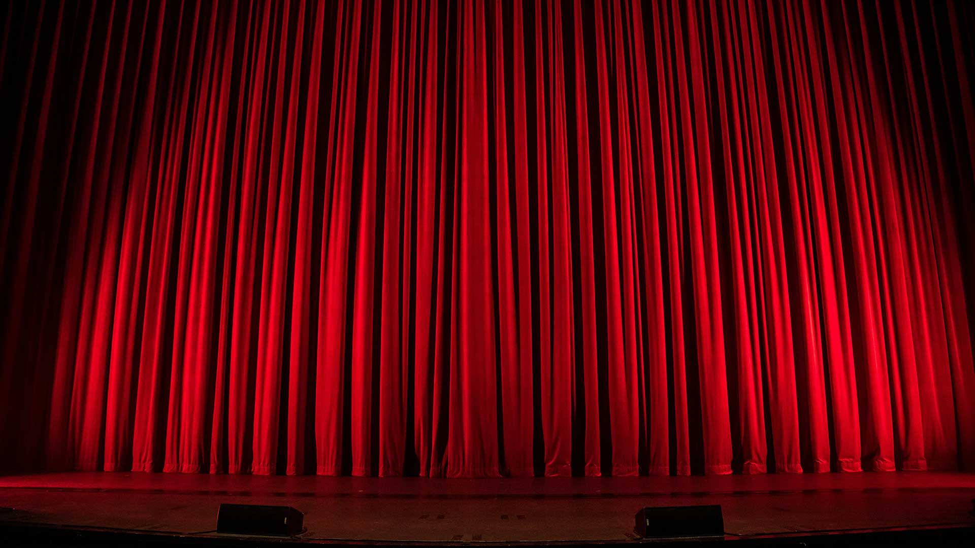 Red velvet theater curtain lit on stage, ready for the show