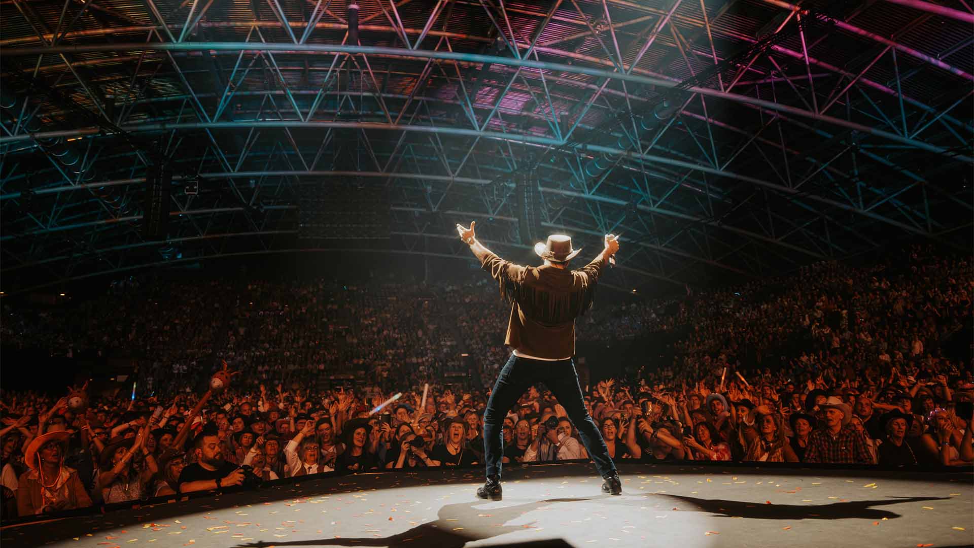 Een artiest in cowboykledij treedt op voor een uitzinnig publiek op Het Schlagerfestival.