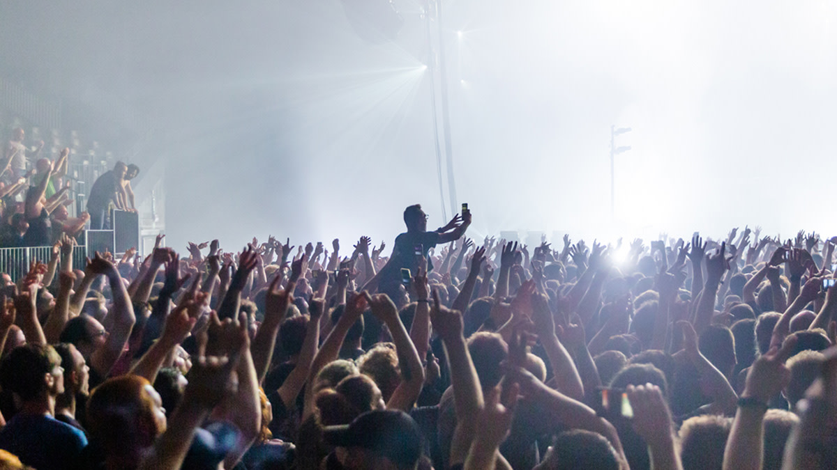 Enthusiastic crowd with their hands in the air during a live concert.