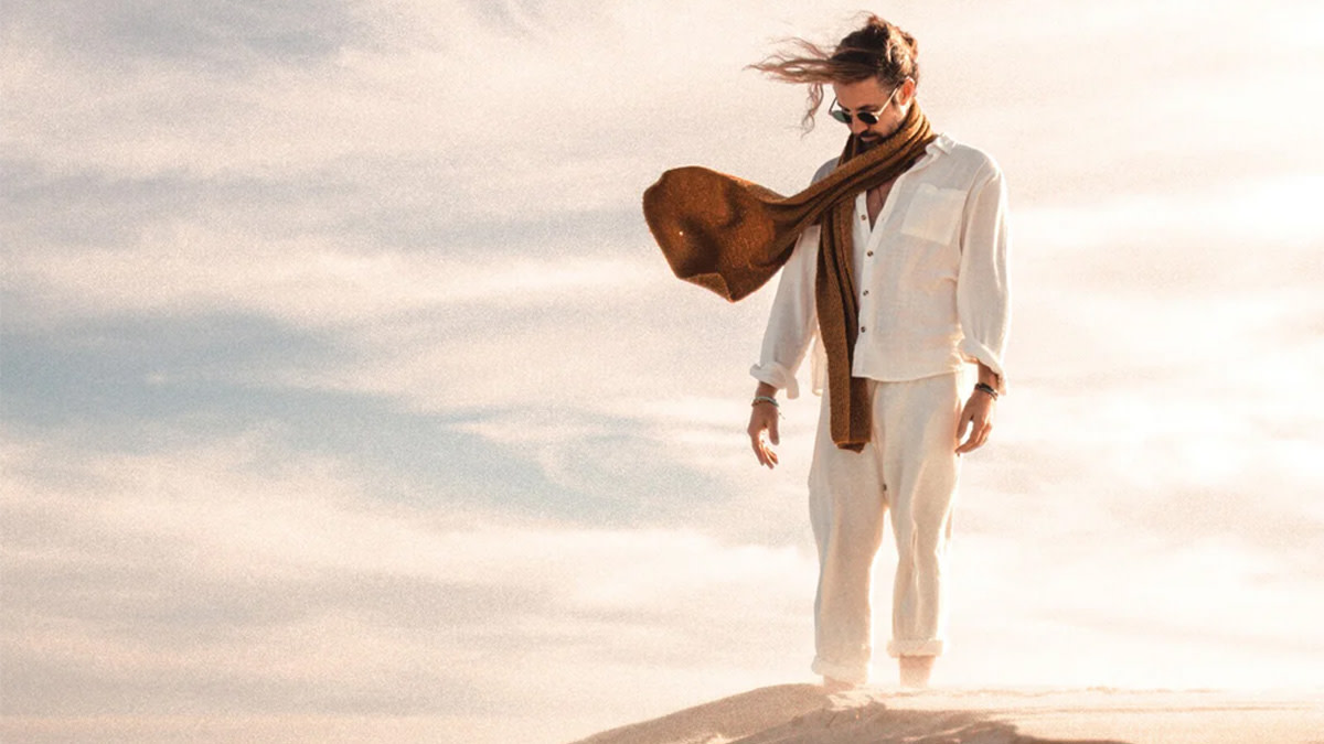 On the cover of the album ‘Feathers and Stone’, Jeremy Loops is standing on top of a sand dune.