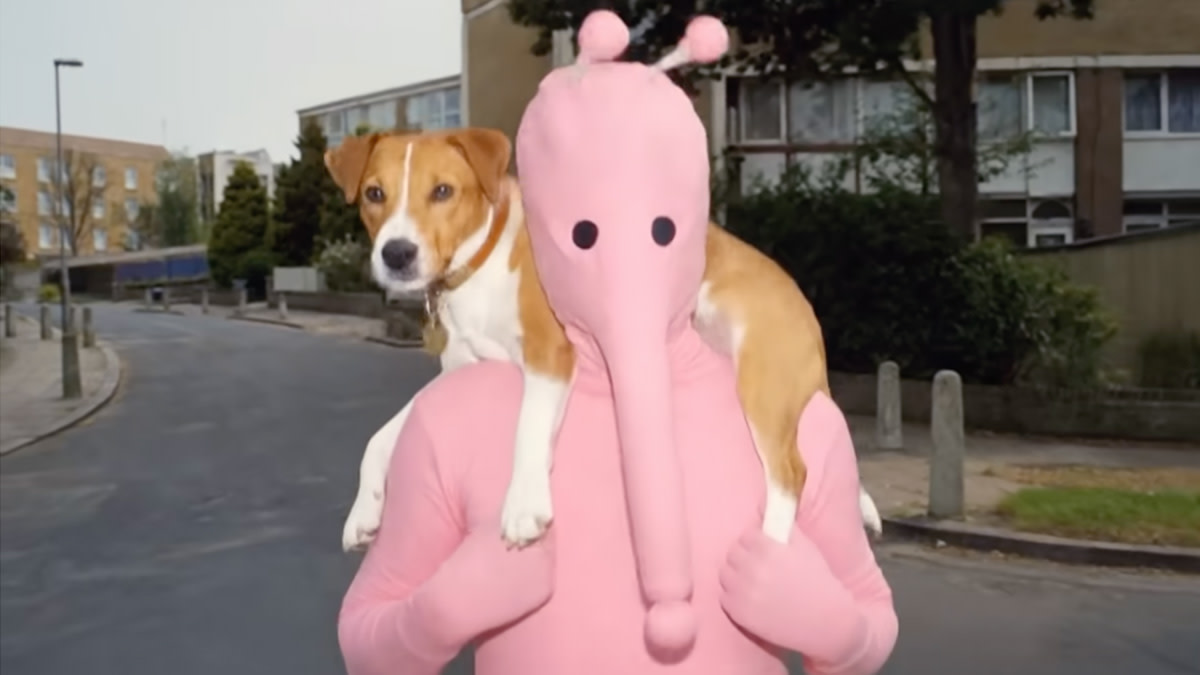 Still from Nothing But Thieves’ “Baby Kool (Evelyn)” music video, showing a pink character carrying a dog on their shoulders.