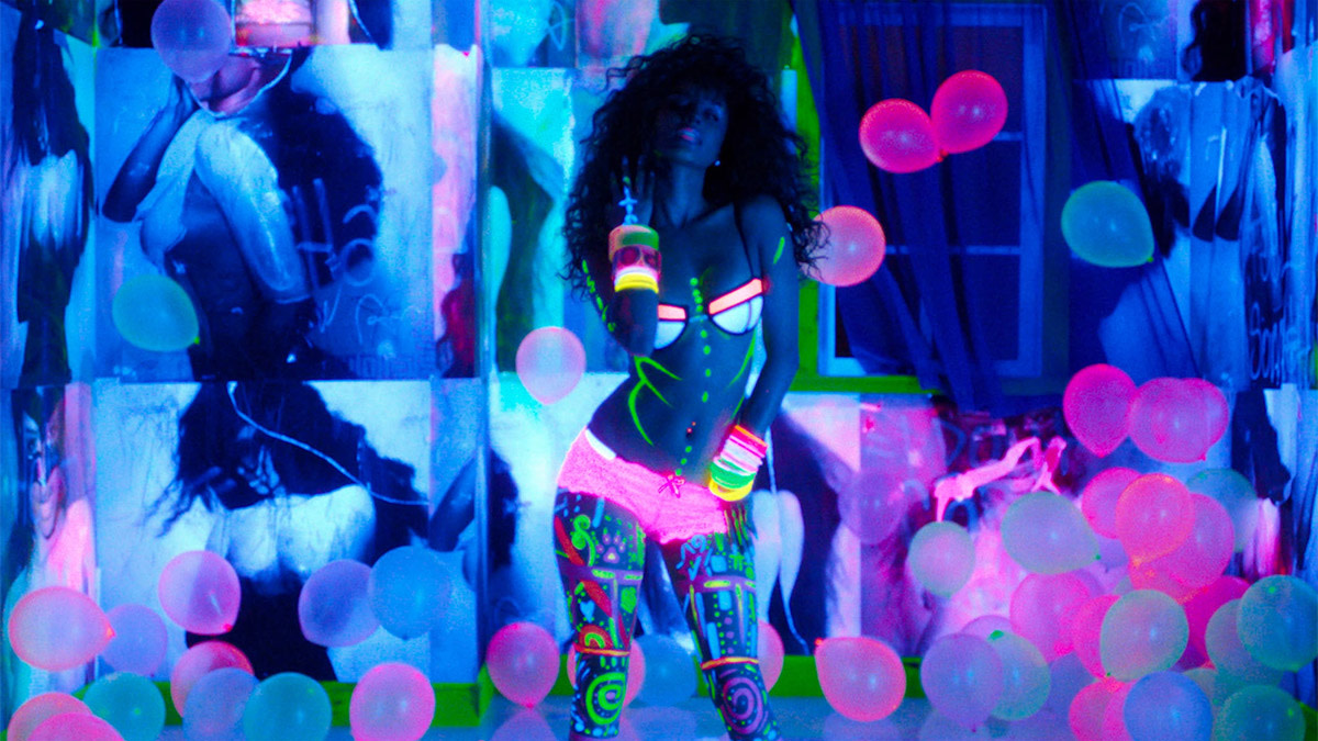 Tyla poseert in een kleurrijke, neonverlichte ruimte met roze en blauwe ballonnen.