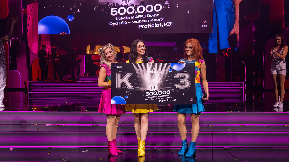 Kathleen, Kristel en Karen houden een plaquette met daarop de vermelding '500.000 tickets in de AFAS Dome'. 