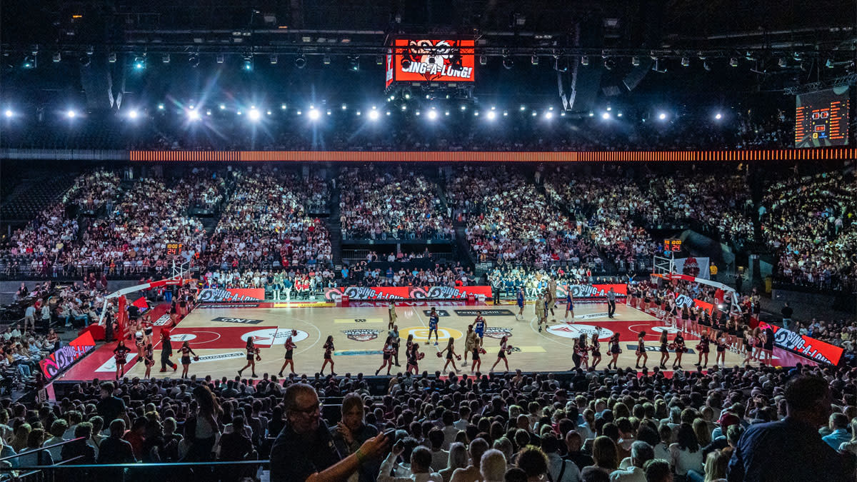 Panoramisch zicht op de AFAS Dome tijdens Night of the Giants, met een volgepakte tribune rond het basketbalveld, cheerleaders op het veld en een spectaculaire licht- en sfeerbeleving in de zaal.
