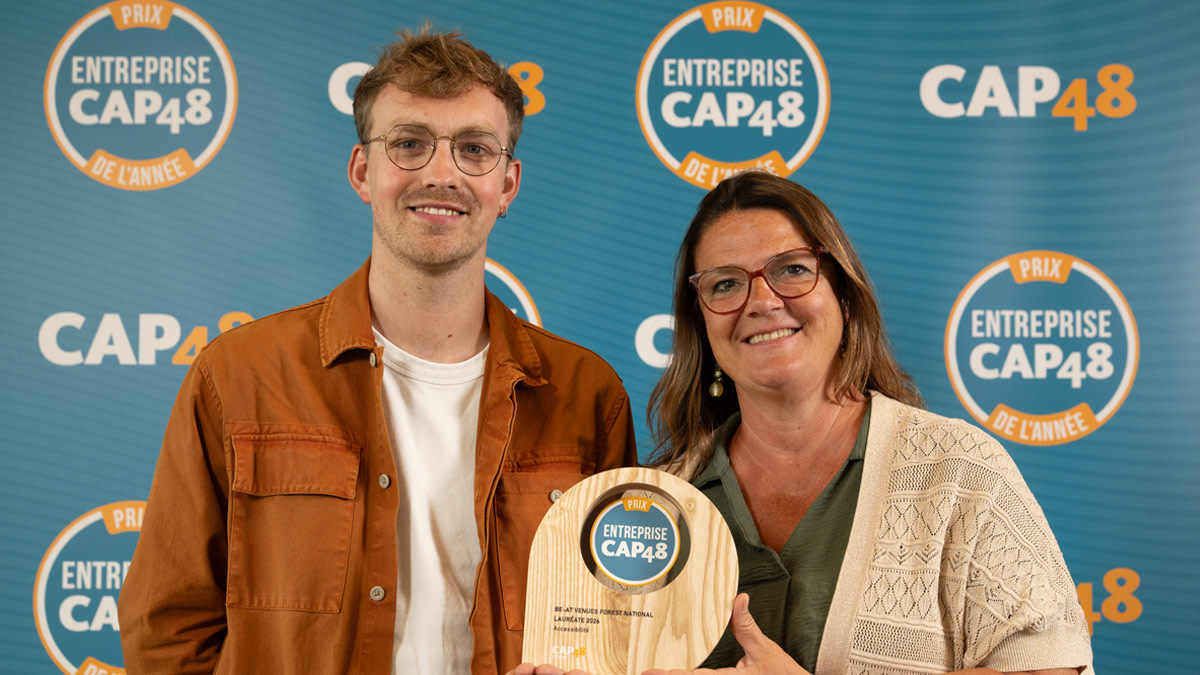 Coralie Berael, directrice de la salle Forest National, reçoit sur scène le prix CAP48 de l'inclusion. En arrière-plan, on aperçoit le logo du prix « Prix Entreprise CAP48 de l’Année ».