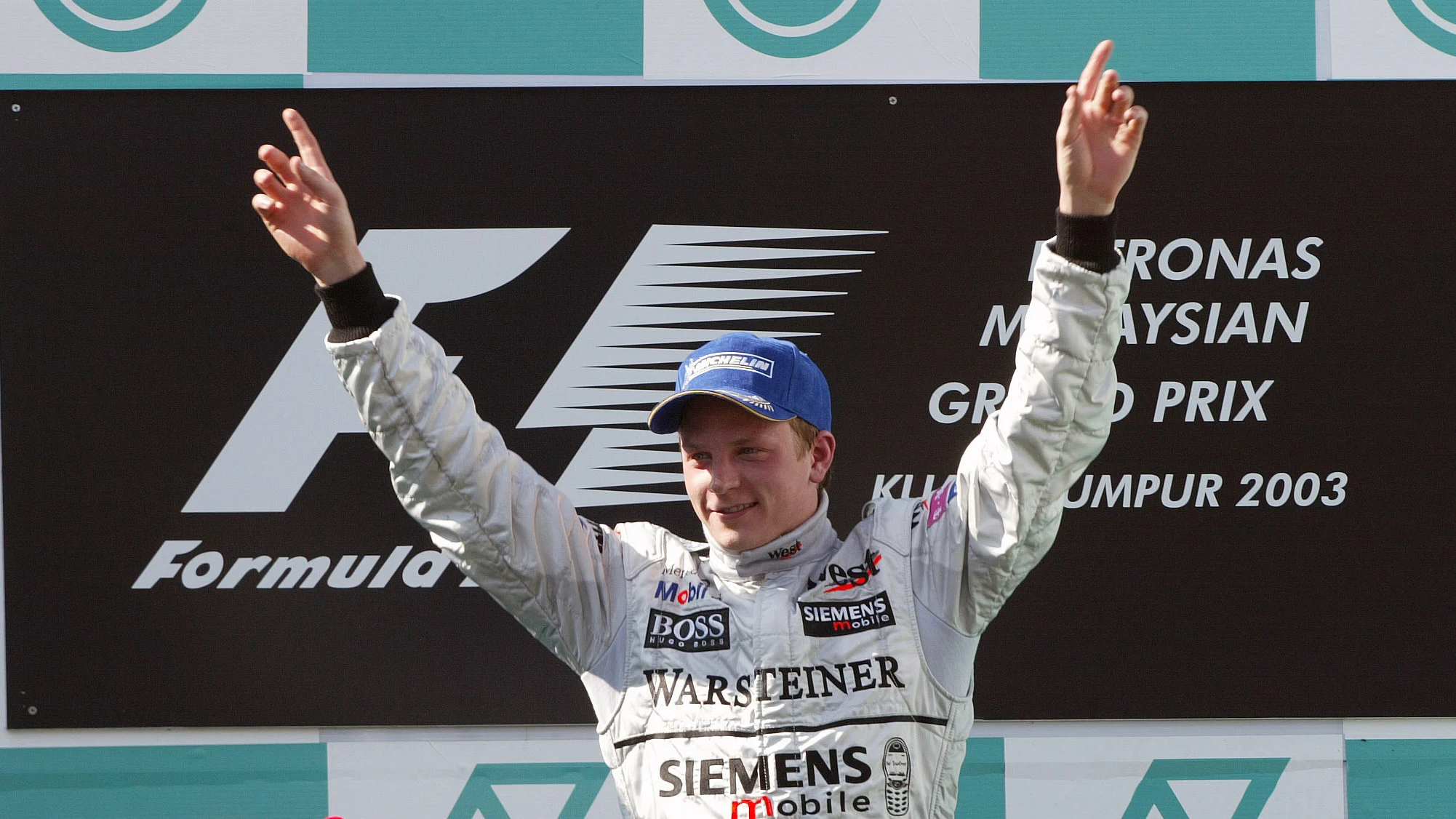 Kimi Raikkonen and McLaren celebrates on the podium after his maiden GP victory in Malaysia