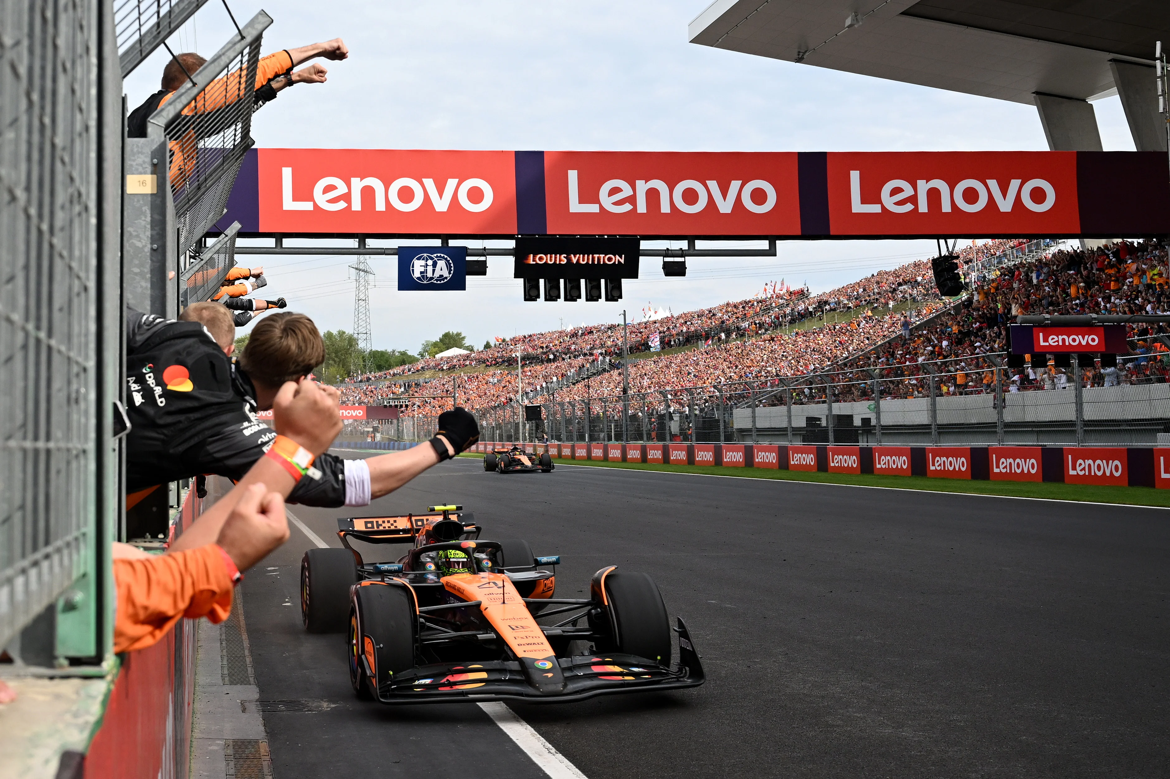 Race winner Lando Norris and Second placed Oscar Piastri cross the finish line to cheers from their team on the pit wall during the Hungarian grand prix.