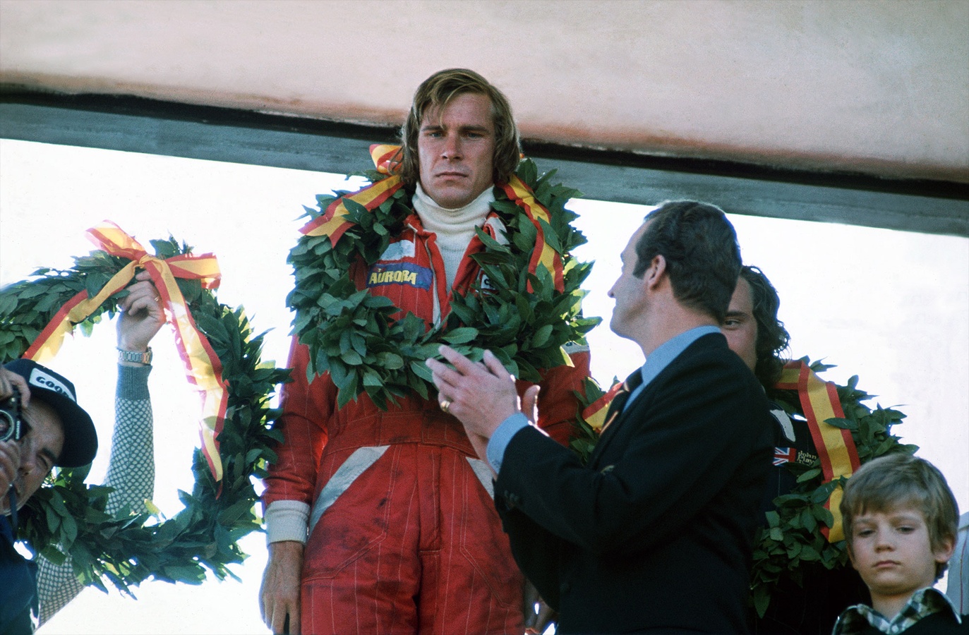 James Hunt wearing a victory wreath at a 1976 McLaren podium celebration in Spain