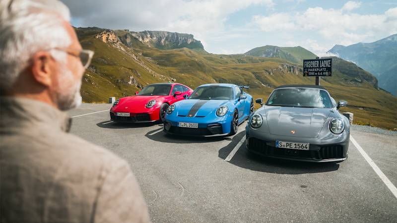 Mann betrachtet rote, blaue und graue Porsche auf Bergstraße.