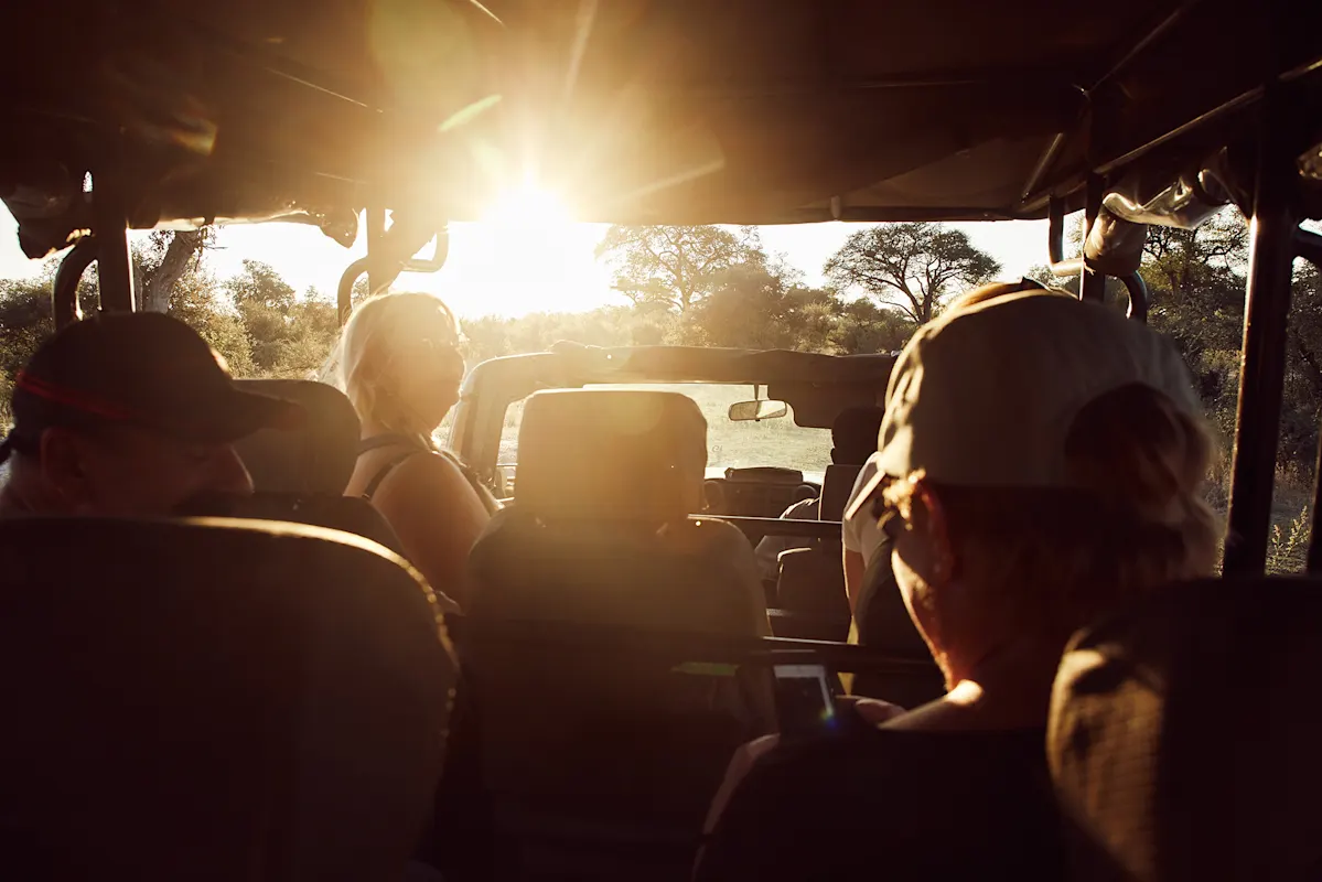 Insassen im Safari-Fahrzeug betrachten die Sonnenuntergangslandschaft.