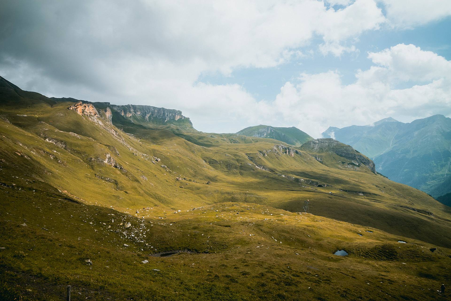 Grüne Hügel und Berge unter teilweise bewölktem Himmel.