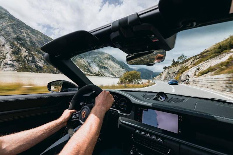 Fahrer im Cabrio auf Bergstraße mit einem Auto voraus.