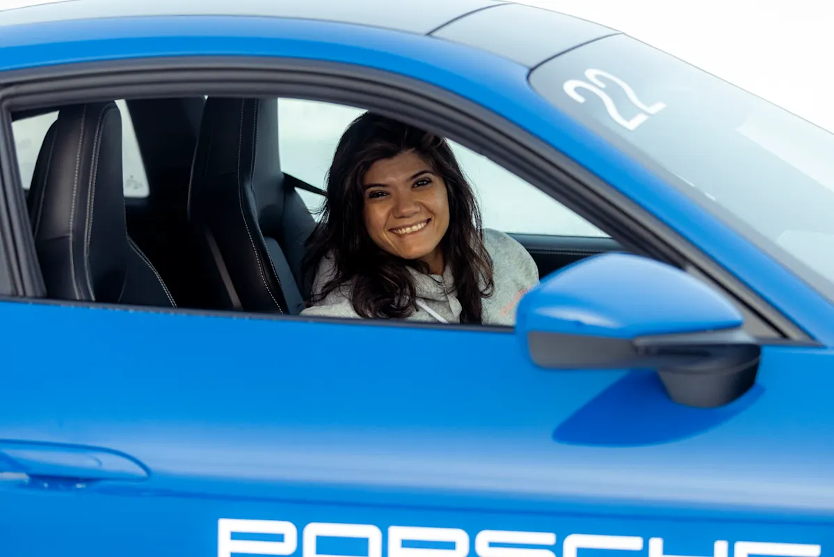 Woman smiling in a blue Porsche with the window down.