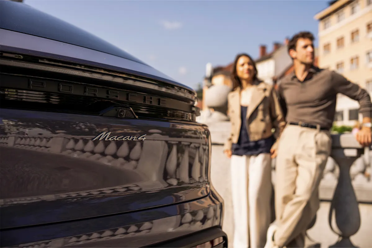 Porsche Macan 4 mit Paar dahinter in der Stadt an einem sonnigen Tag.