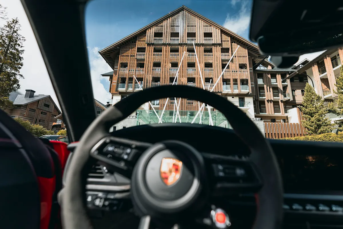 Blick durch Porsche-Windschutz auf Holzhotel und Lenkrad.
