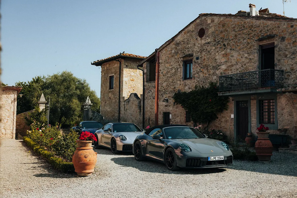 Drei Porsche parken bei Steingebäuden mit Pflanzen.