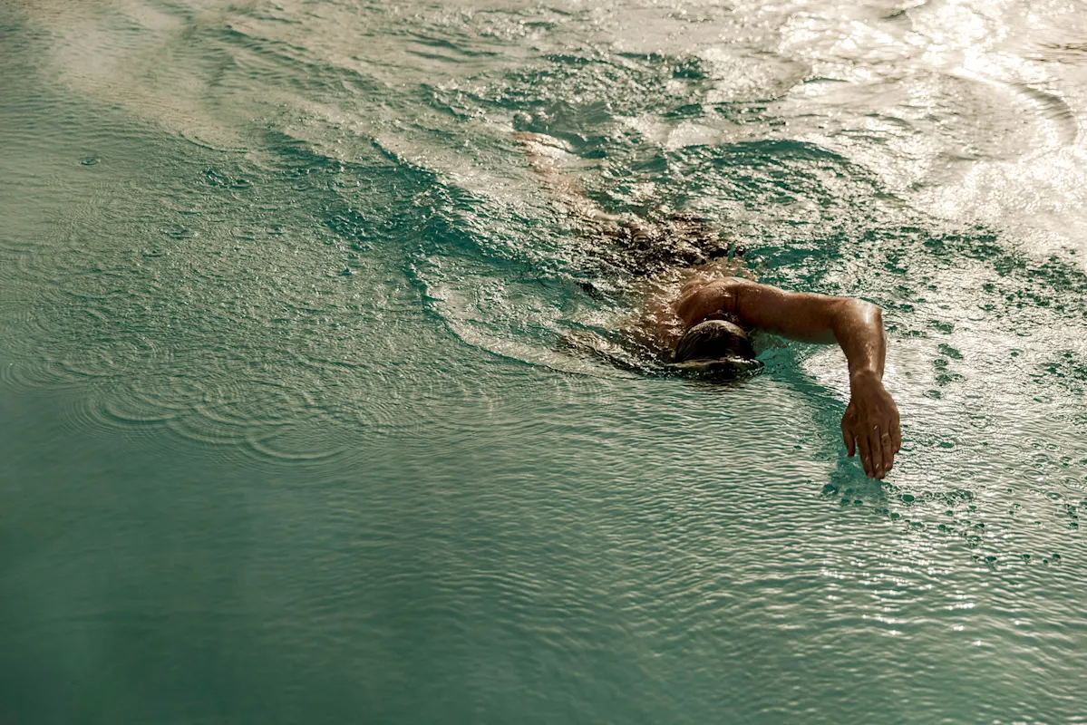 Swimmer doing freestyle stroke in pool with water splashes.