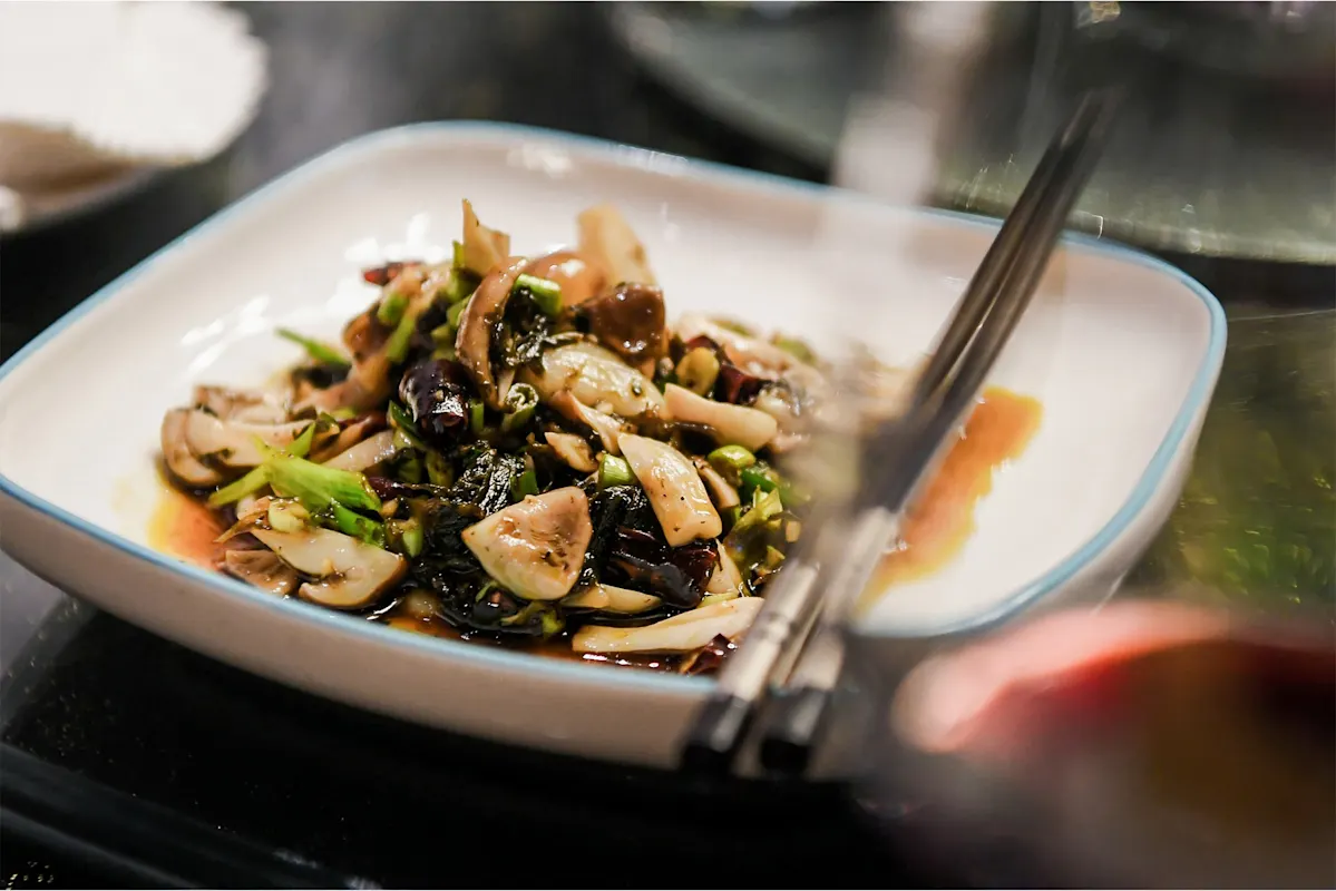 Gebratene Pilze und Gemüse mit Soße und Stäbchen.