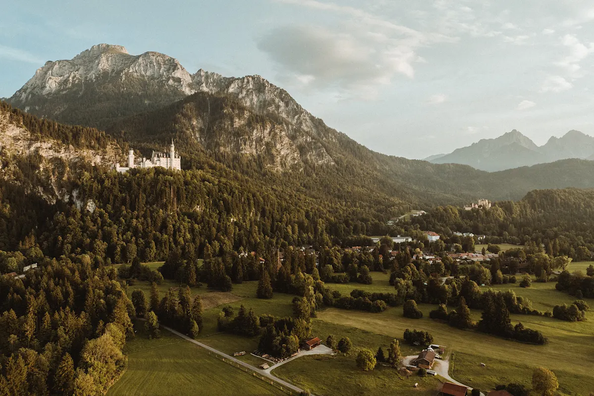 Burg an bewaldetem Hang mit Tal- und Bergblick.
