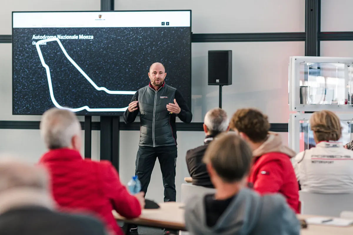 An instructor gives a presentation about the Monza circuit to a group of participants in a classroom setting.