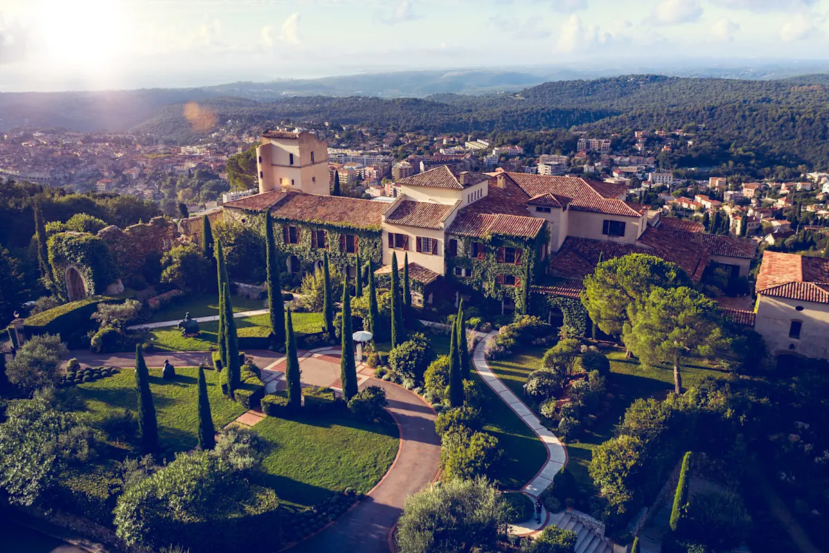 Luftbild einer Villa mit Gärten in Hügeln an einem teilweise bewölkten Tag.
