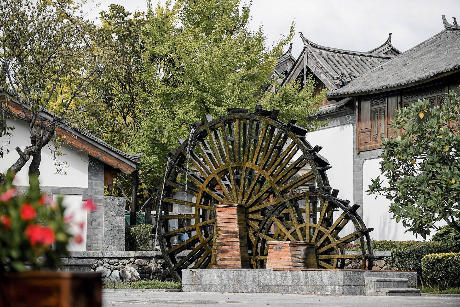 Holzwasserrad bei ostasiatischen Bauten mit Grün.
