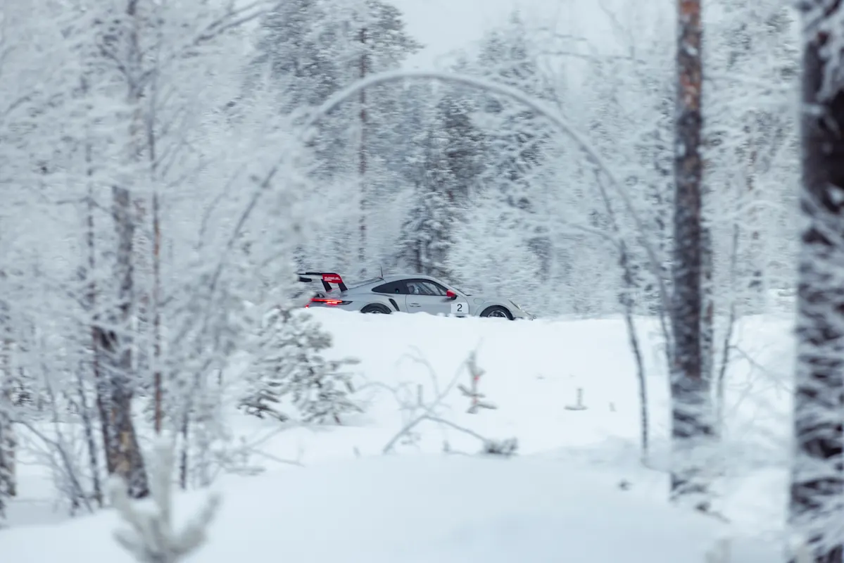 A Porsche drives through a snowy forest with number 2.