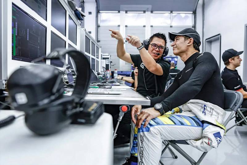 Porsche Fahrer überprüft Daten mit Ingenieur in der Garage.