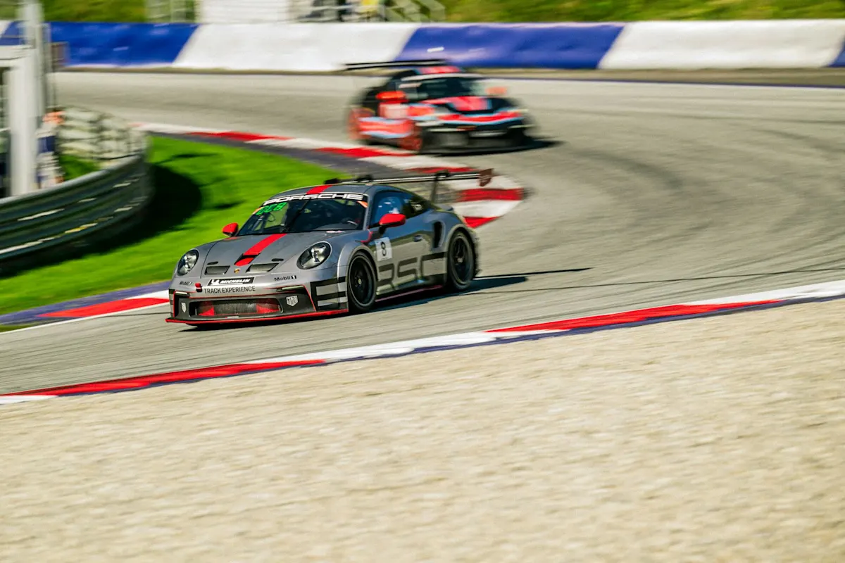 Porsche race car leading on track in daytime race.