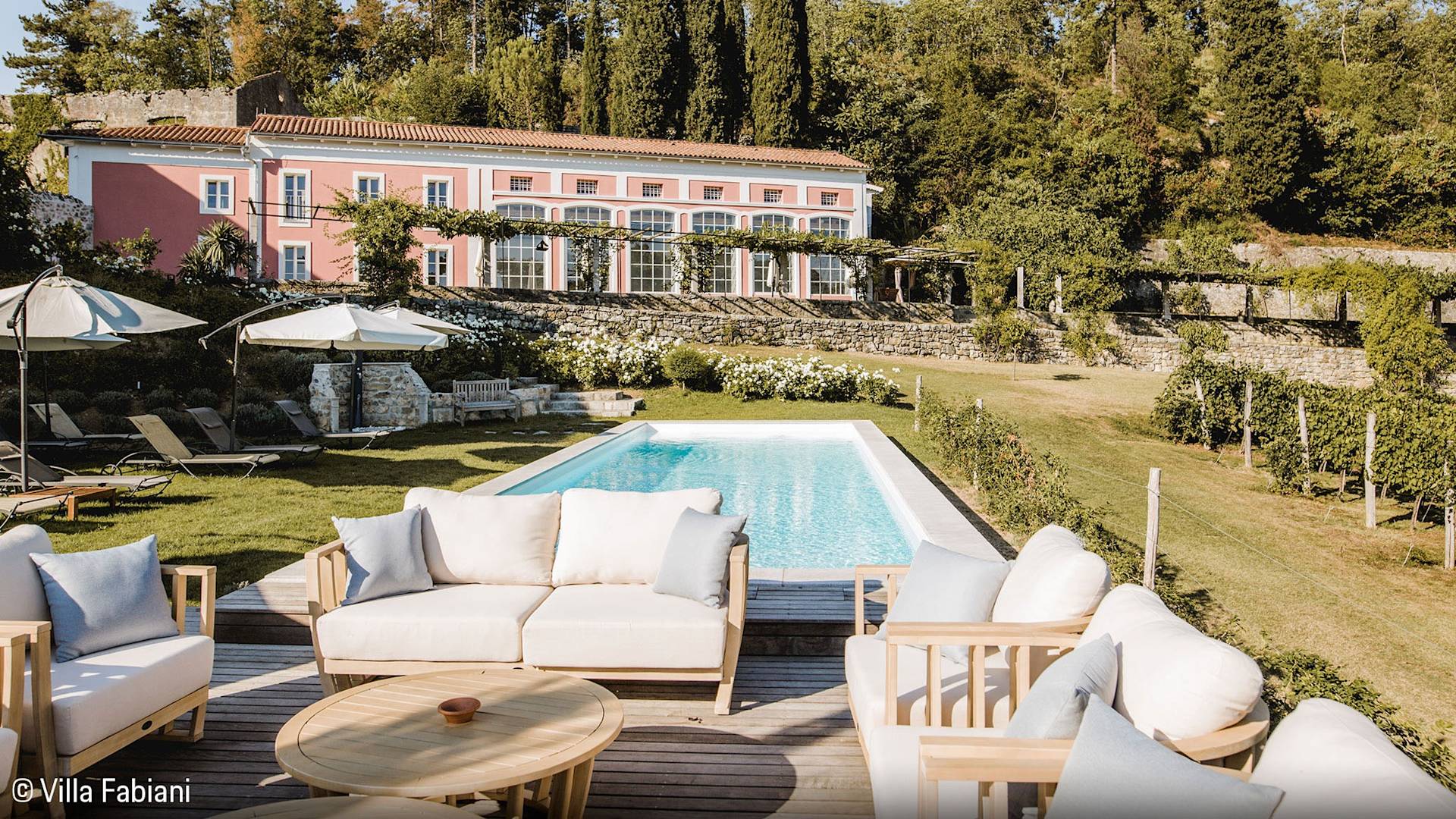 Luxusvilla mit Pool, Außenbereich und üppigen Gärten an einem sonnigen Tag.