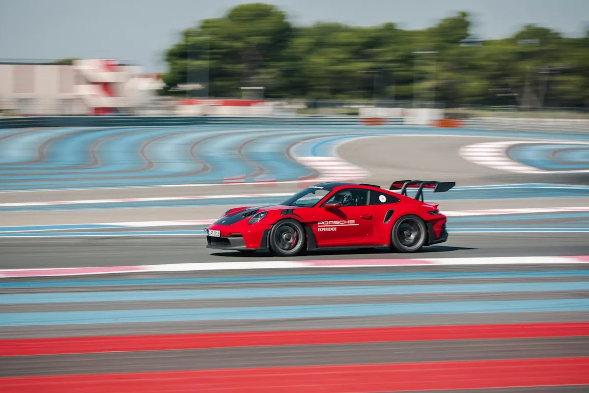 A red Porsche on racetrack, zooming with motion blur, vibrant colors.