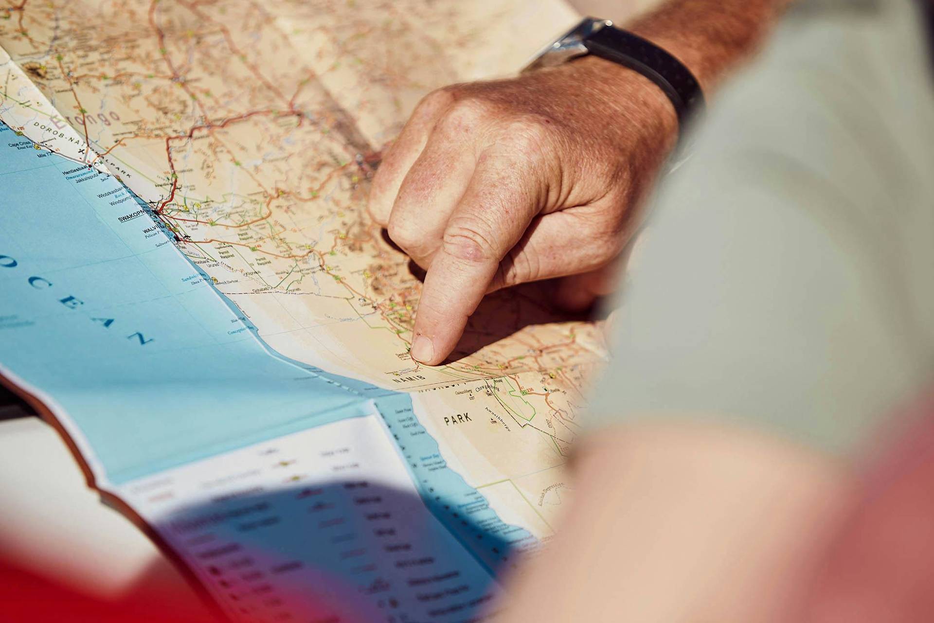 Person zeigt auf Karte mit Küstengebieten und Straßen.