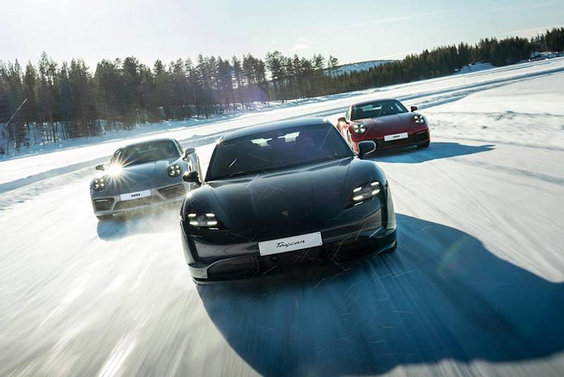 Porsche Sportwagen auf verschneiter Strecke, schwarz, silber und rot, unter strahlender Sonne.