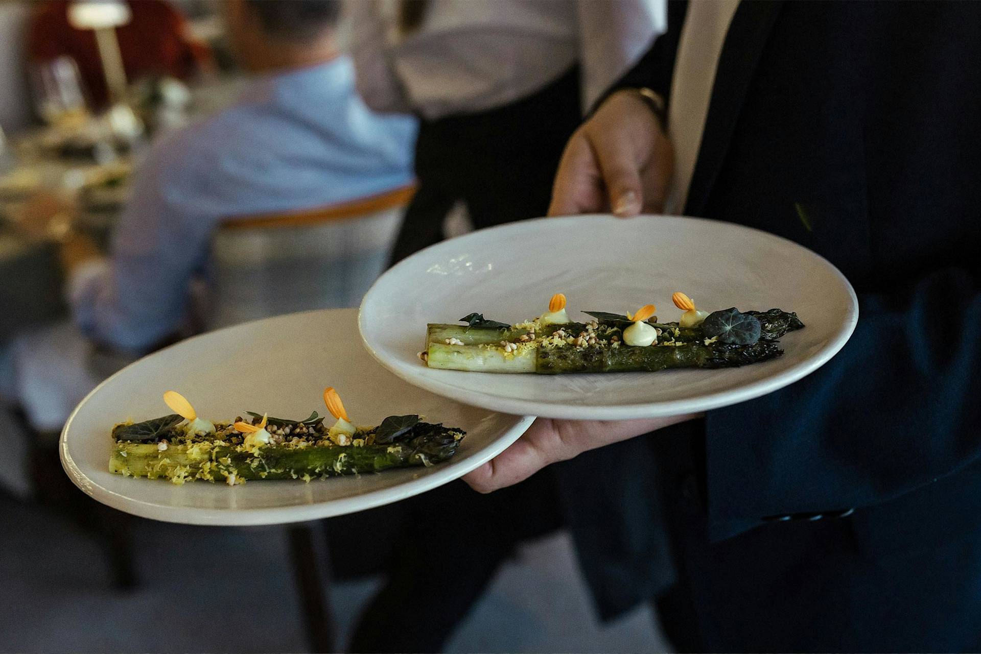Person hält Teller mit garniertem Gemüse im Restaurant.