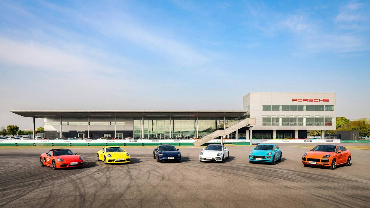 Porsche Auto in lebhaften Farben vor modernem Gebäude parkend. Logo sichtbar. Himmel klar blau.