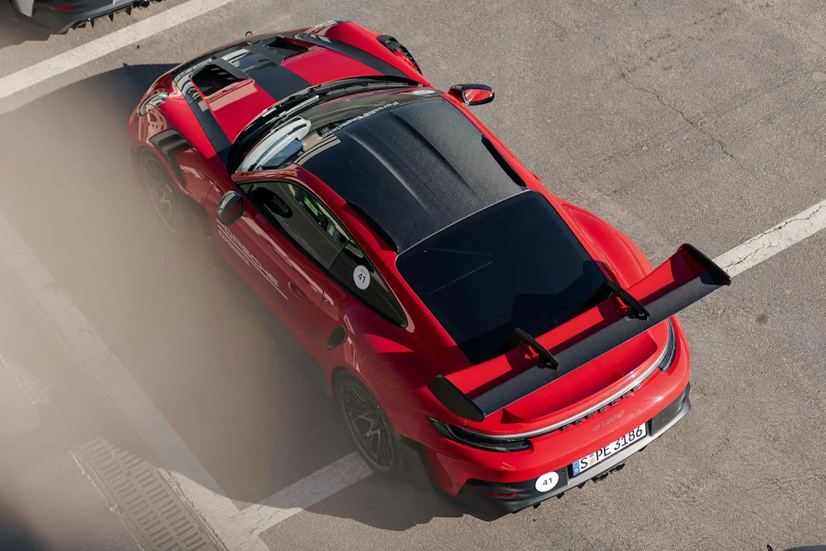 Obenansicht eines roten Porsche-Sportwagens mit Heckspoiler, geparkt auf einem markierten Platz.