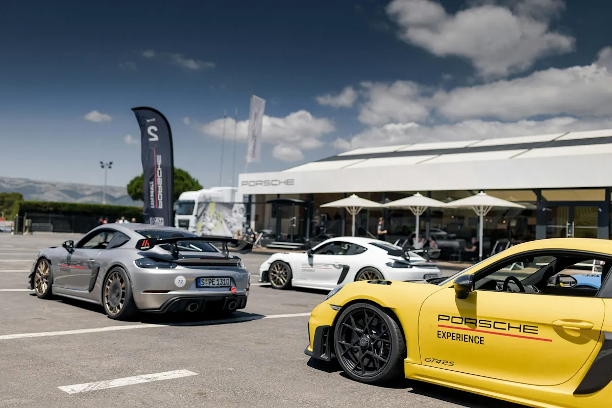 Porsche Sportwagen vor modernem Autohaus an sonnigem Tag, gelber GT2 RS im Vordergrund.