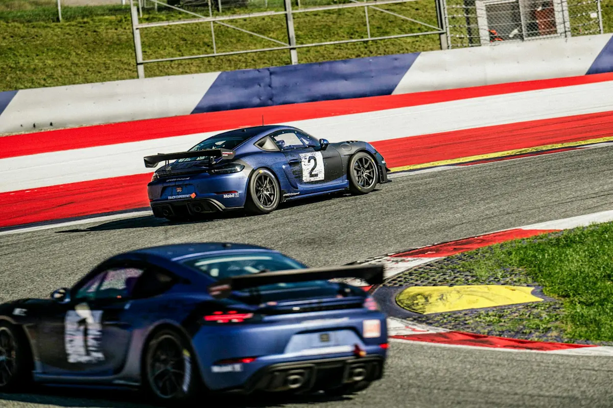 Blauer Porsche-Sportwagen fährt auf Strecke mit roten und weißen Randsteinen im Hintergrund.